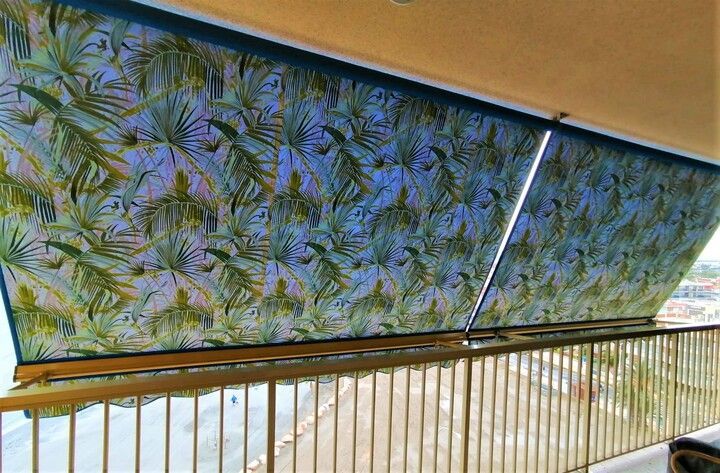 Un balcón con un toldo azul y verde encima.