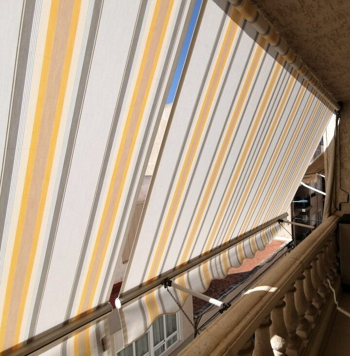 Un toldo de rayas amarillas y blancas en un balcón.