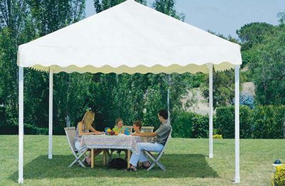 Una familia está sentada a una mesa bajo una carpa blanca.
