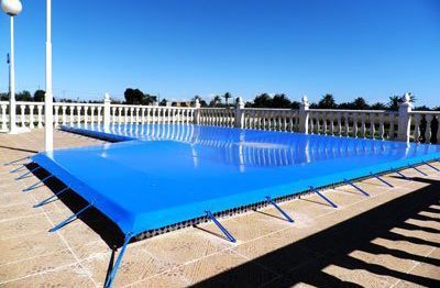 Una lona azul cubre una piscina en un patio.