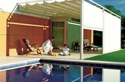 Una mujer y dos niños están sentados en un patio junto a una piscina.