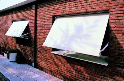 Un edificio de ladrillo con dos ventanas con toldos blancos.