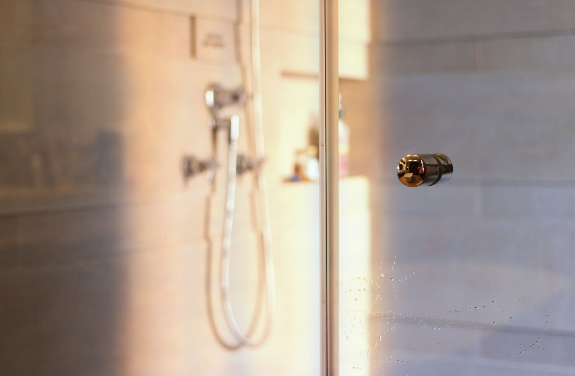 Una cabina de ducha con puerta de cristal y cabezal de ducha.