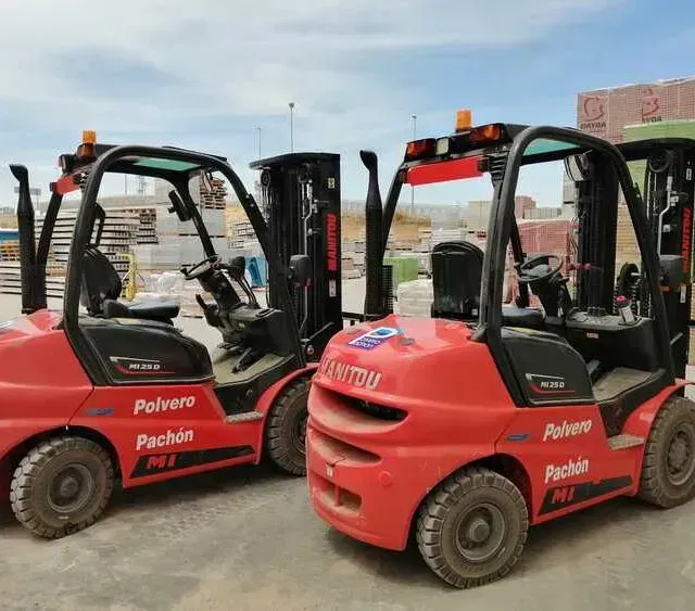 Dos carretillas elevadoras rojas están estacionadas una al lado de la otra en un estacionamiento.