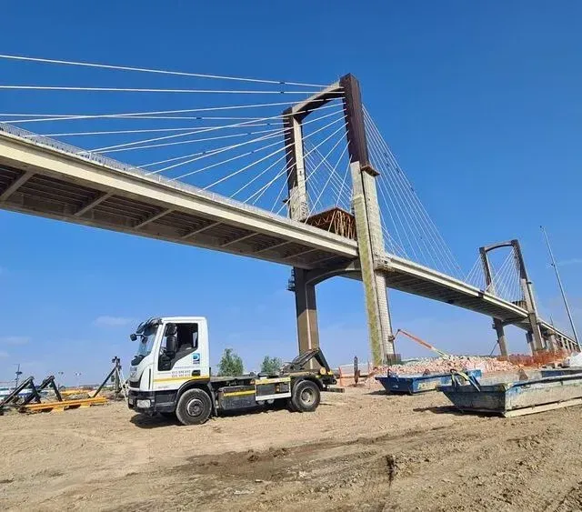 Una grúa está estacionada debajo de un puente.