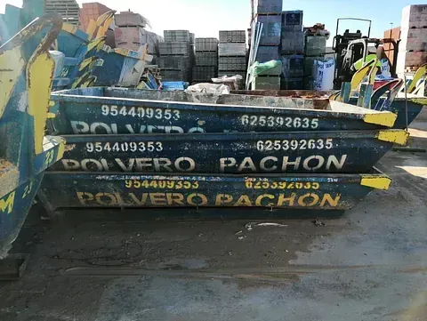 Tres contenedores de basura están apilados uno encima del otro en un estacionamiento.
