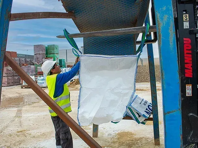 Un hombre está cargando una bolsa en una carretilla elevadora Manitou.