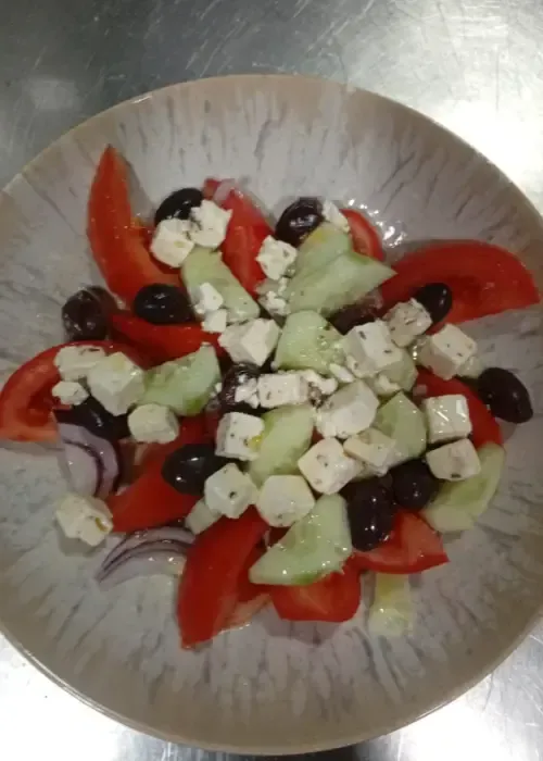 Ensalada griega en un bol: tomates, pepinos, aceitunas, queso feta y cebolla roja.