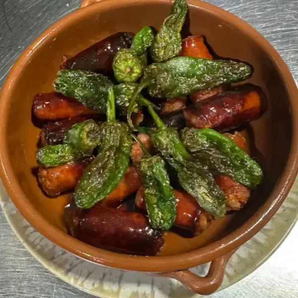 Cuenco de chorizo frito y pimientos de Padrón en cazuela de barro.