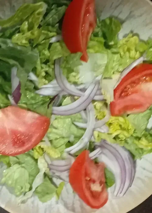 Ensalada con lechuga, tomates en rodajas y cebolla roja.