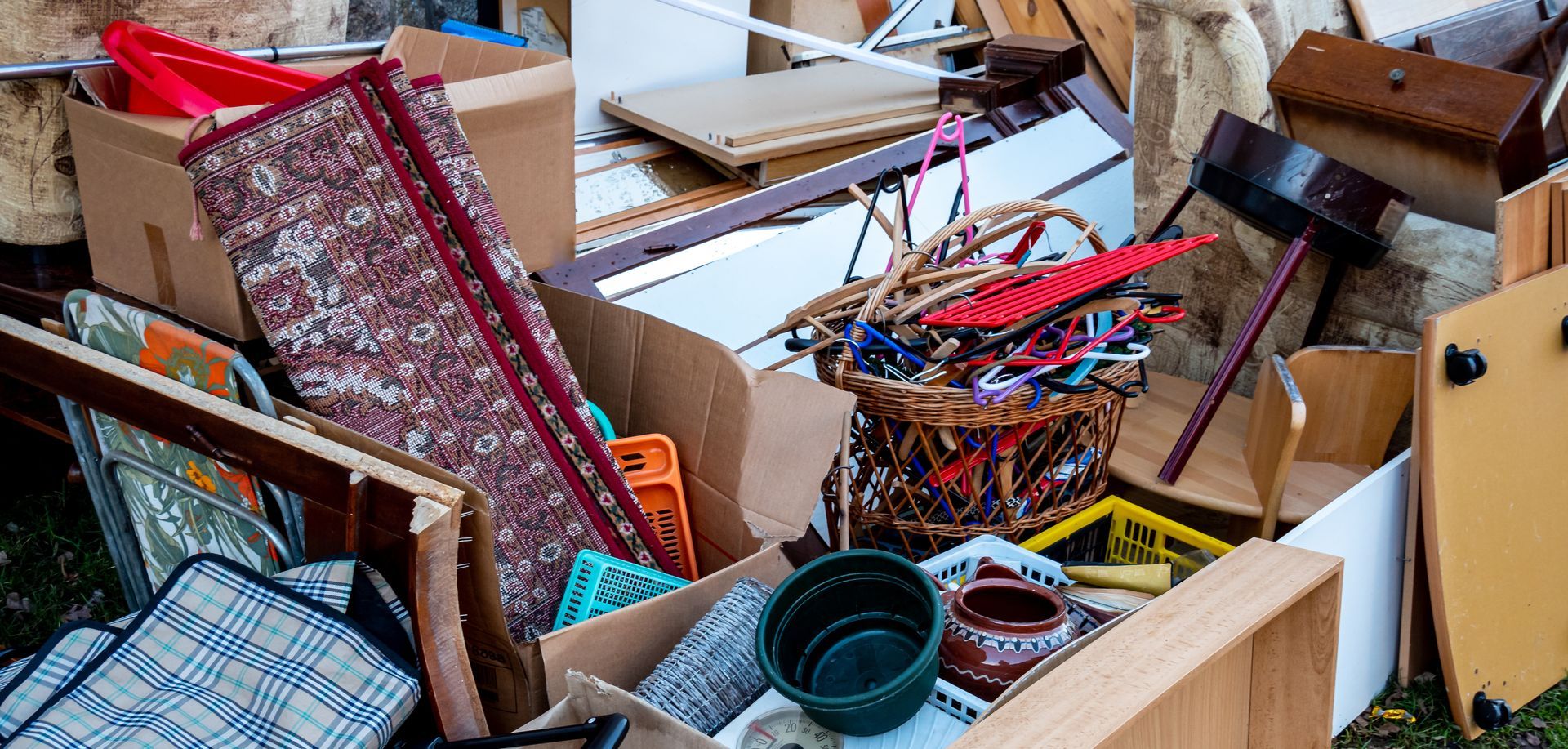 Ein Haufen weggeworfener Gegenstände, darunter Kisten, ein Teppich und ein Korb.
