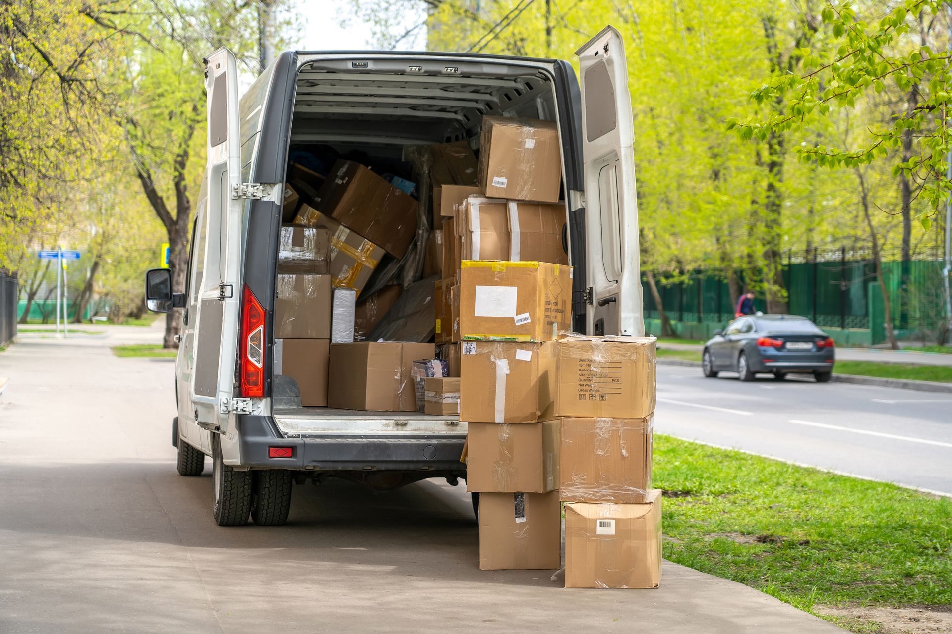 Ein weisser Lieferwagen parkte auf der Strasse, vollbeladen mit Kartons, die Türen standen offen.
