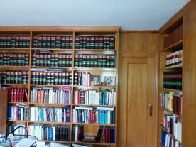 Estanterías llenas de libros; estantes de madera y puerta en una habitación.