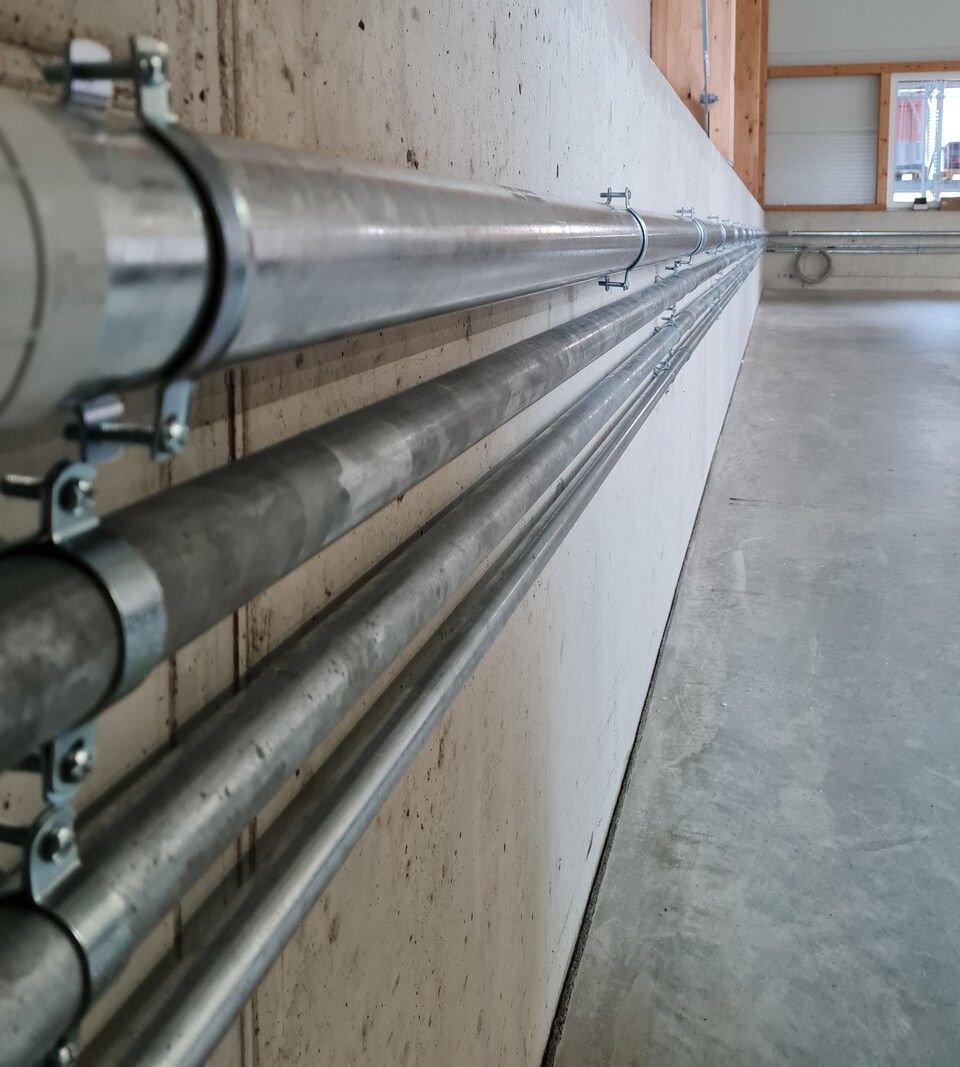 Verzinkte Metallrohre, die an einer Betonwand befestigt sind.