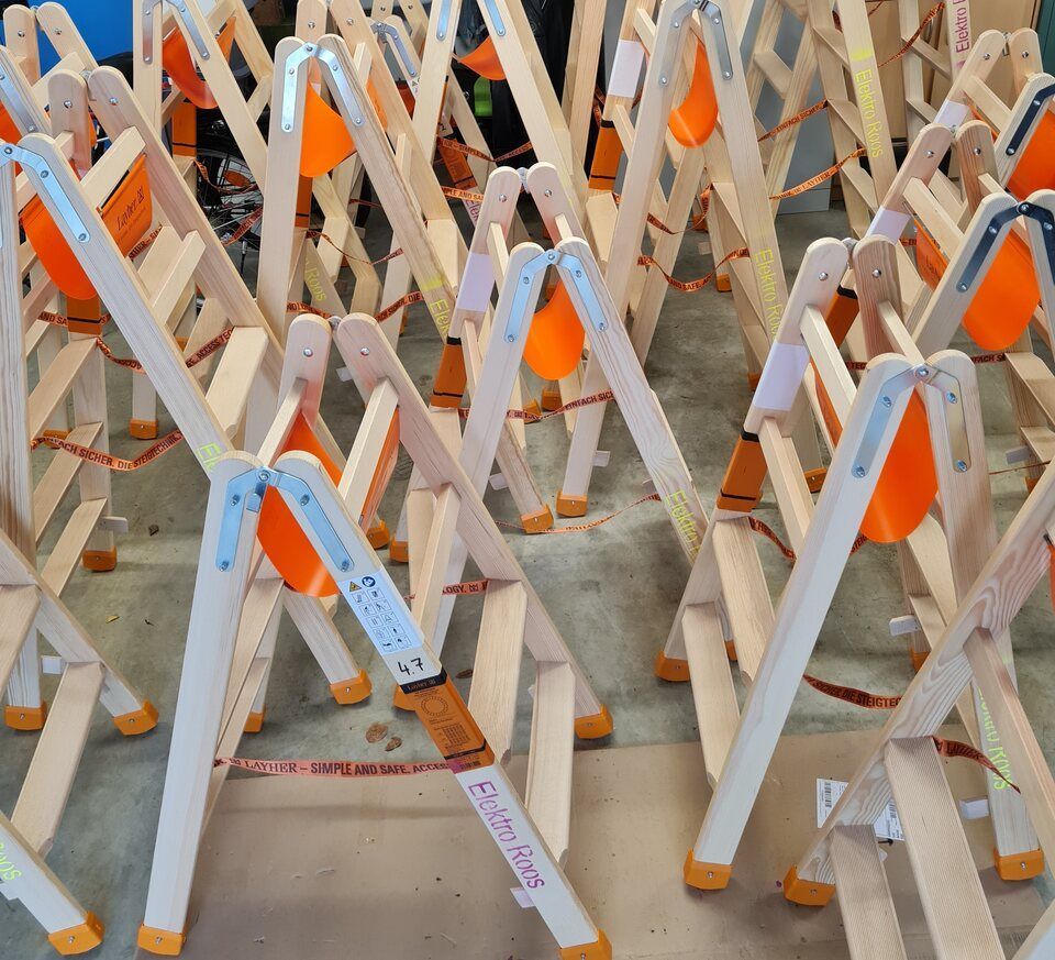 Holzleitern mit orangefarbenen Sicherheitskegeln auf einem Betonboden.