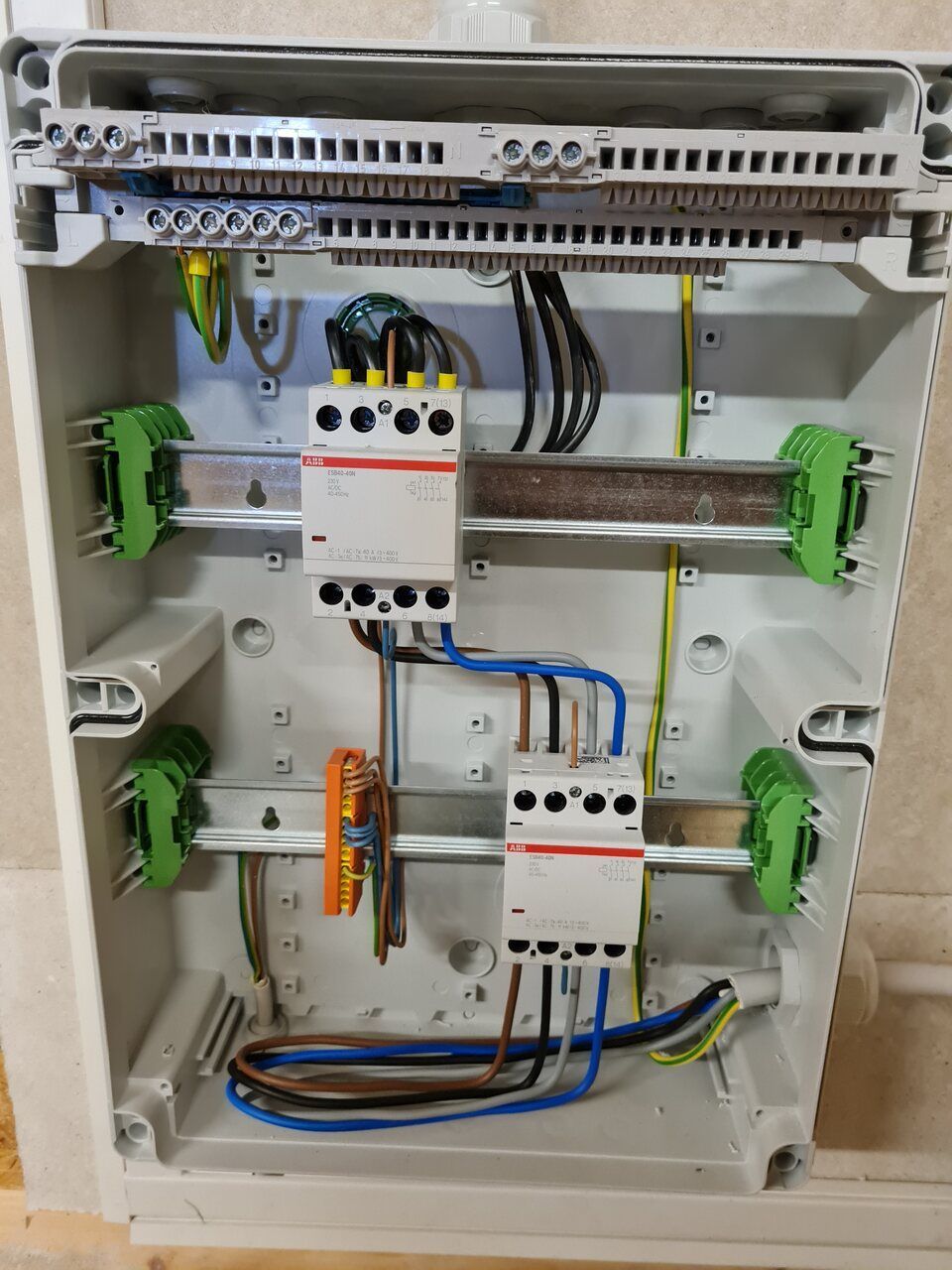 Elektrischer Verteilerkasten mit Verkabelung, Leistungsschaltern und Klemmenblöcken in einem weißen Gehäuse.