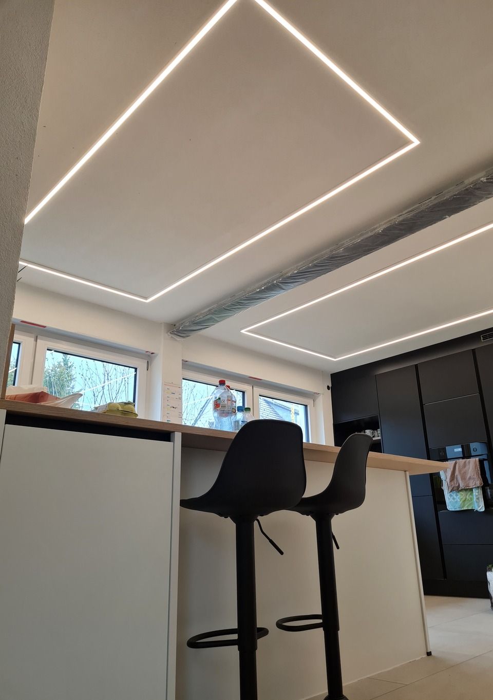 Küche mit modernen, weißen Deckeneinbaustrahlern. Barhocker stehen an der Theke.