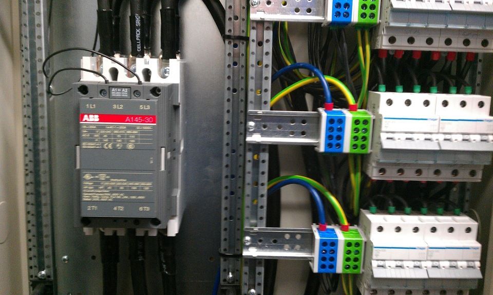 Schalttafel mit grauen Leitungsschutzschaltern, Drähten und Klemmenblöcken.