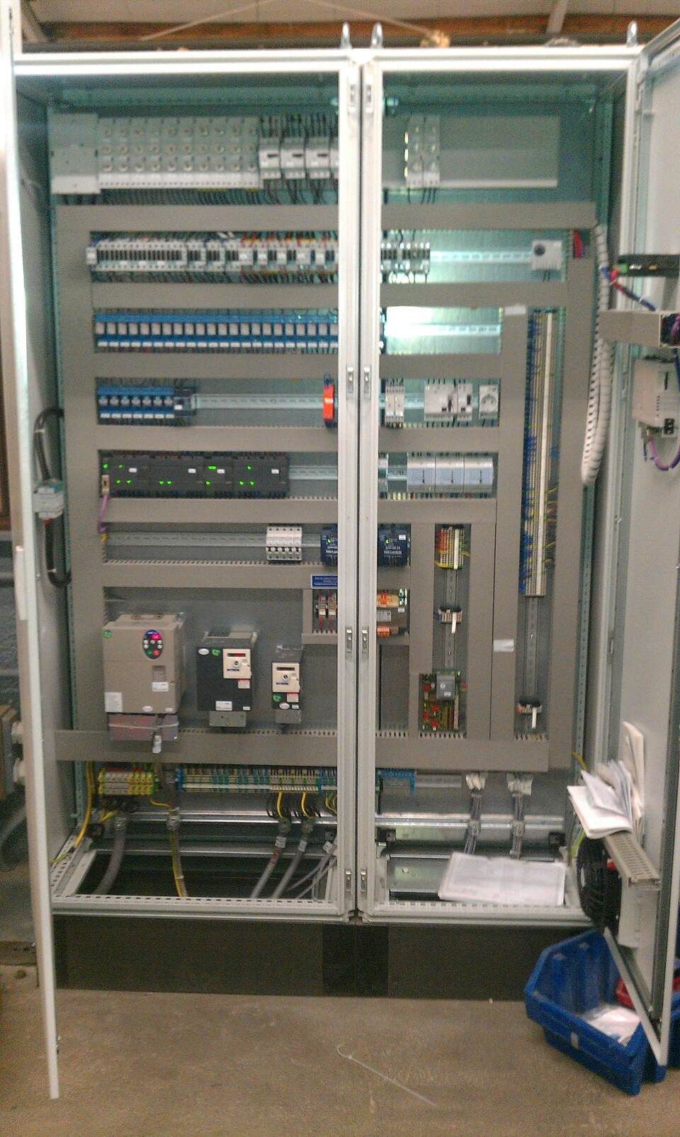 Elektrischer Schaltschrank mit zahlreichen Leistungsschaltern, Relais und anderen Bauteilen, montiert in einem Metallgehäuse.