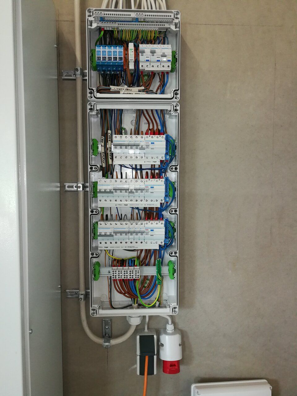 Elektrischer Verteilerkasten mit Sicherungsautomaten und Verkabelung, an der Wand montiert.
