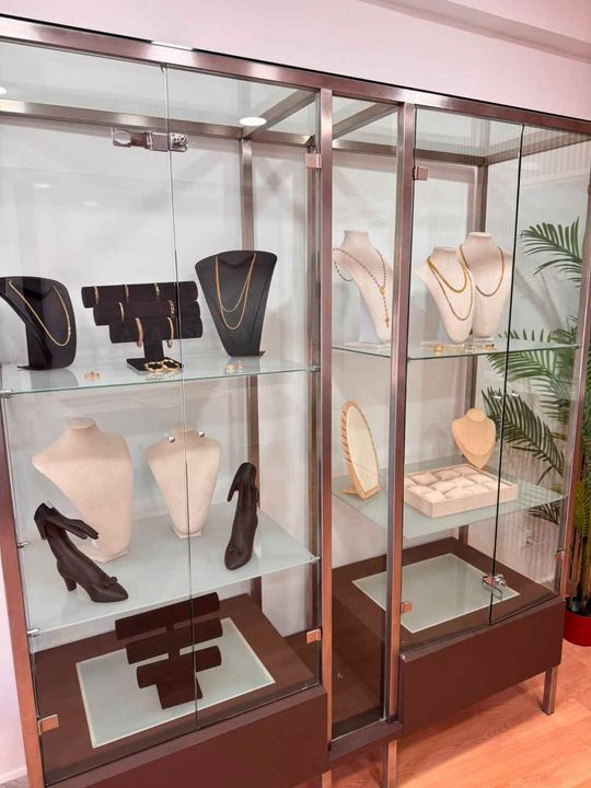 Vitrinas de cristal para joyería con collares y soportes decorativos en el interior de una tienda.