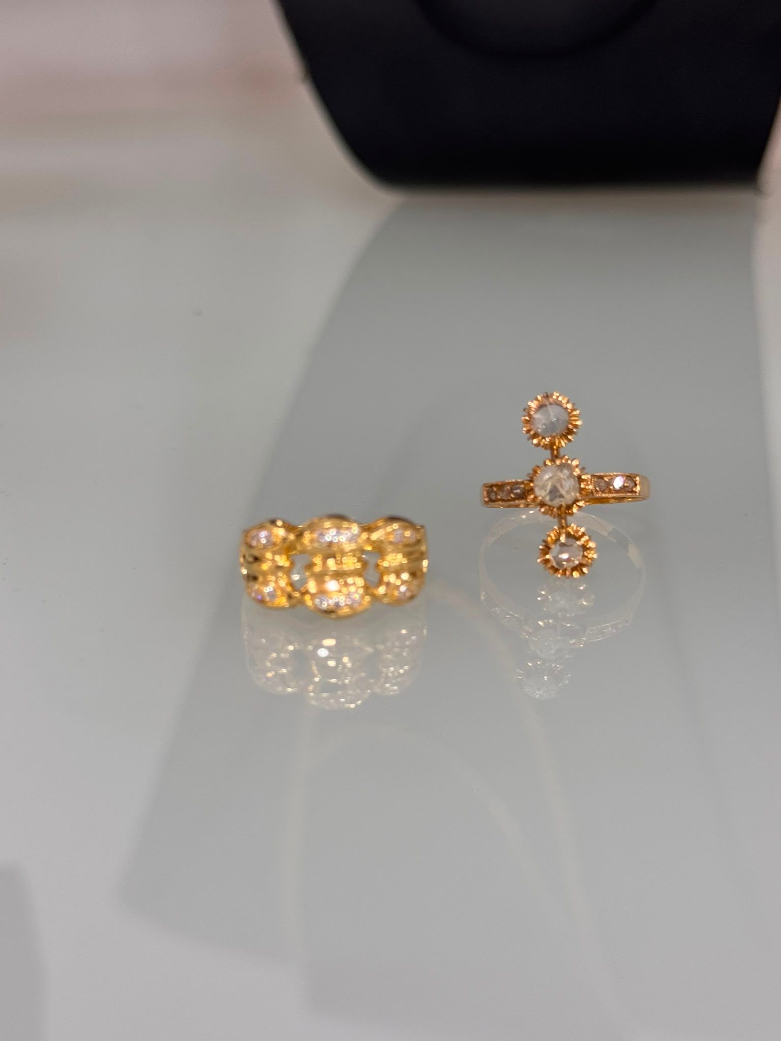 Anillo y pendientes de oro con piedras transparentes expuestas sobre una superficie reflectante.