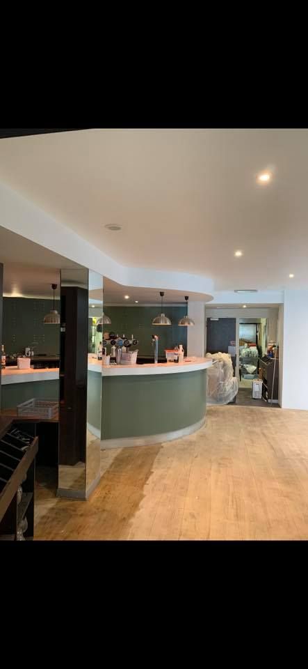 Vue intérieure d'un bar avec un comptoir incurvé et un sol en bois.