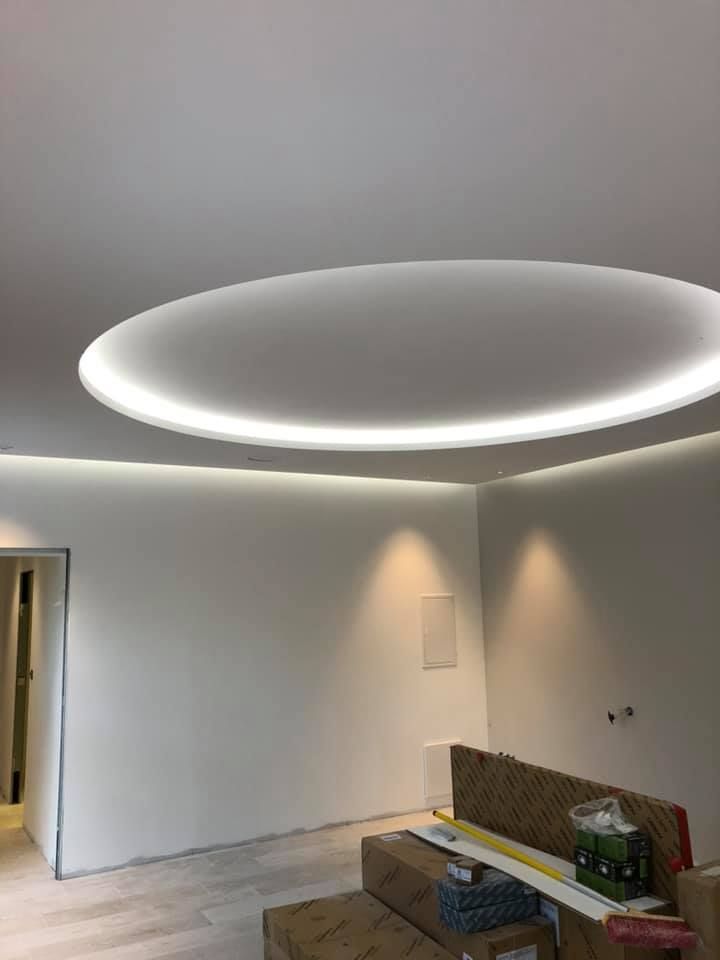 Pièce intérieure avec murs blancs, spots encastrés au plafond et luminaire central circulaire.