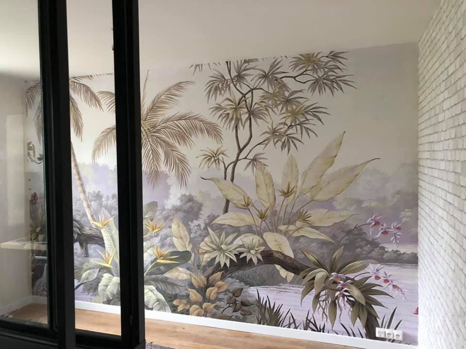 Fresque botanique sur un mur à cadre sombre, avec un mur de briques à droite.