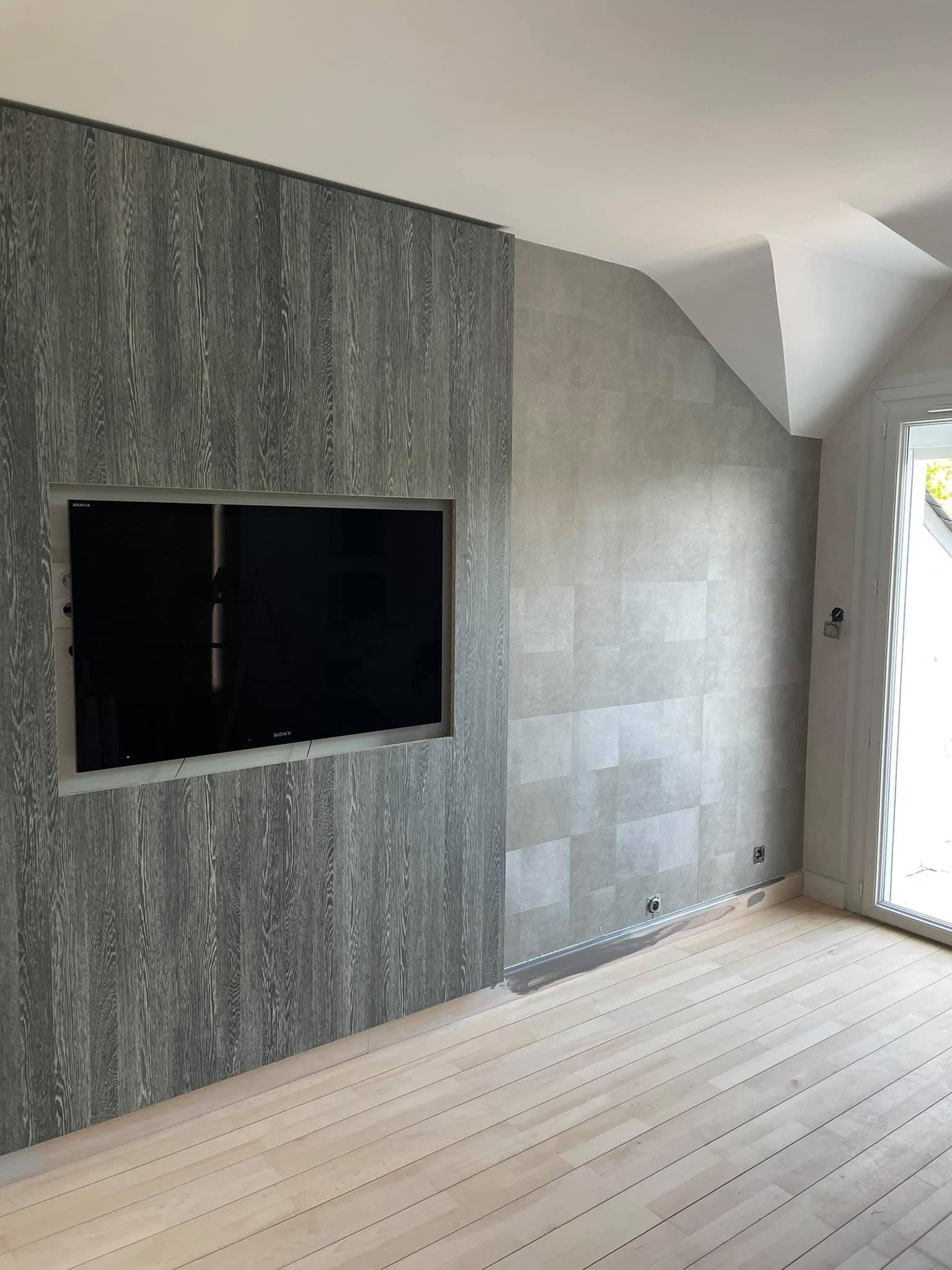 Pièce vide avec un mur en pierre grise, un rectangle noir incrusté et un parquet clair.