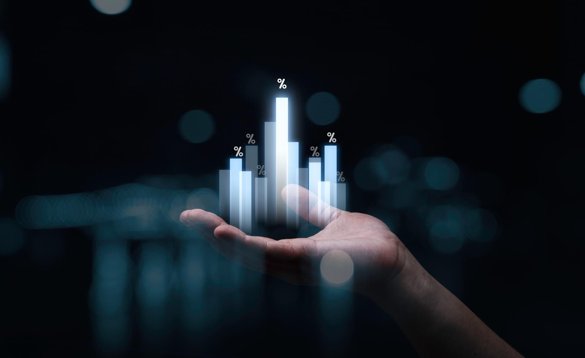 Eine Hand hält ein Hologramm von Balkendiagrammen in der Hand