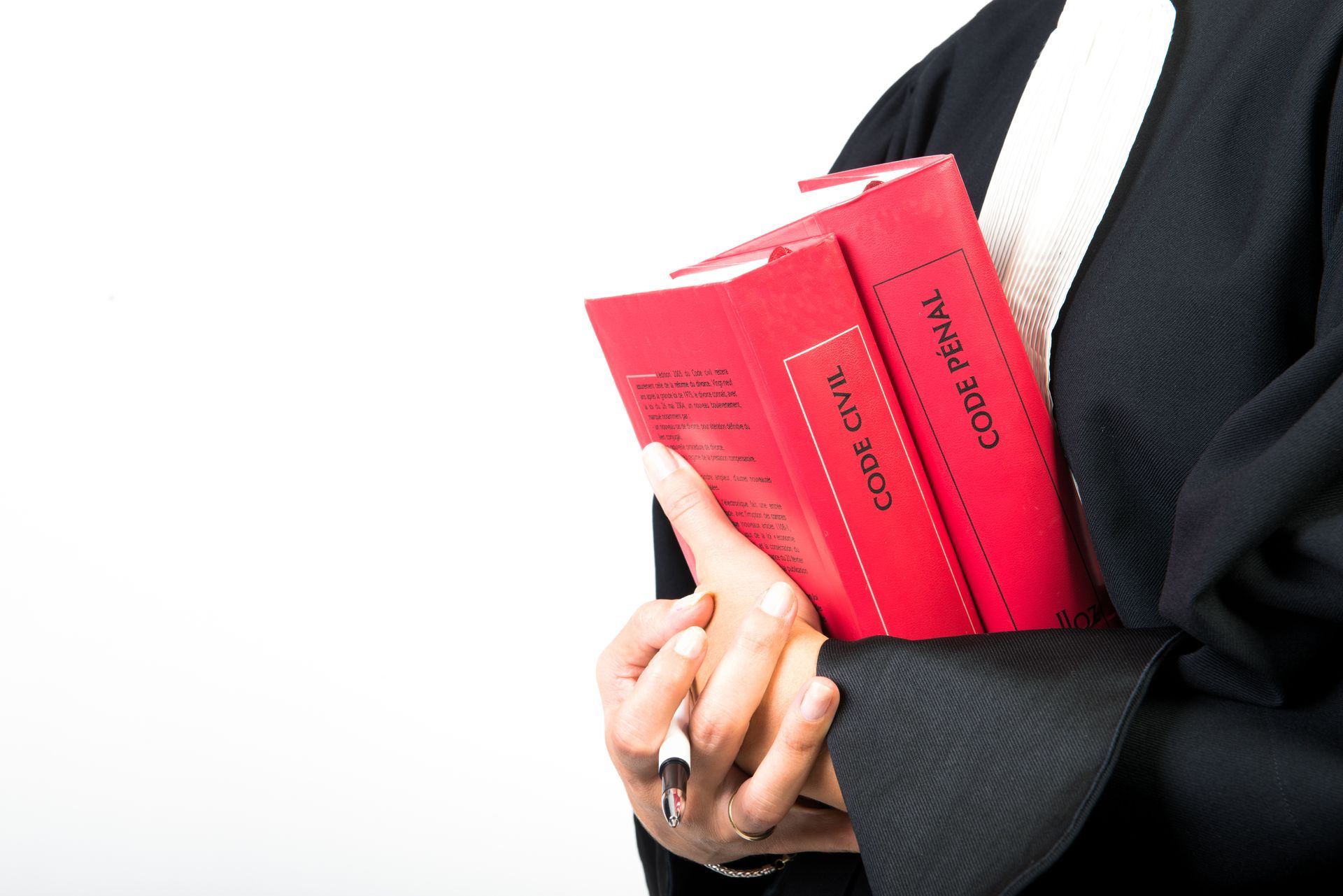 Personne vêtue d'une robe noire tenant des livres de lois rouges et un stylo.