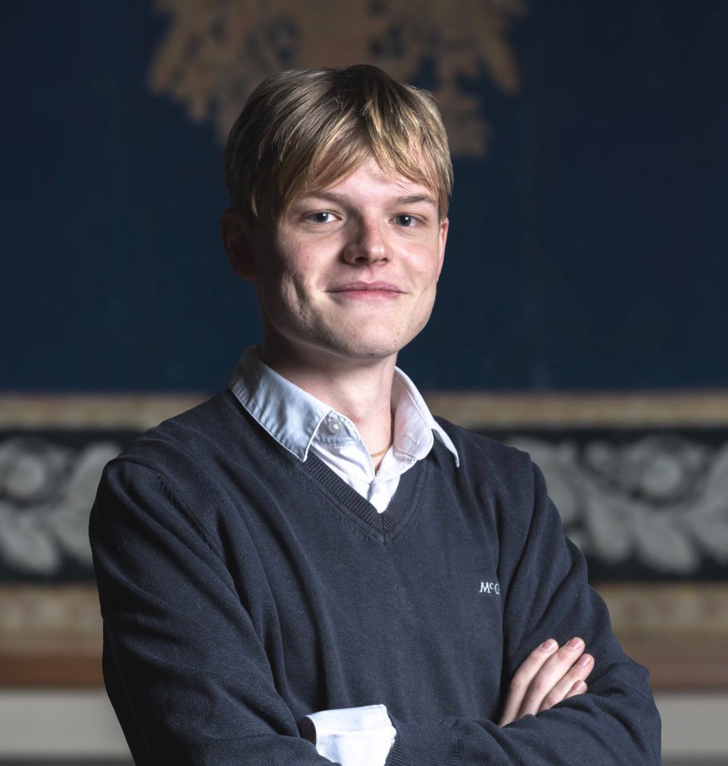 Personne vêtue d'une robe noire tenant des livres de lois rouges et un stylo.