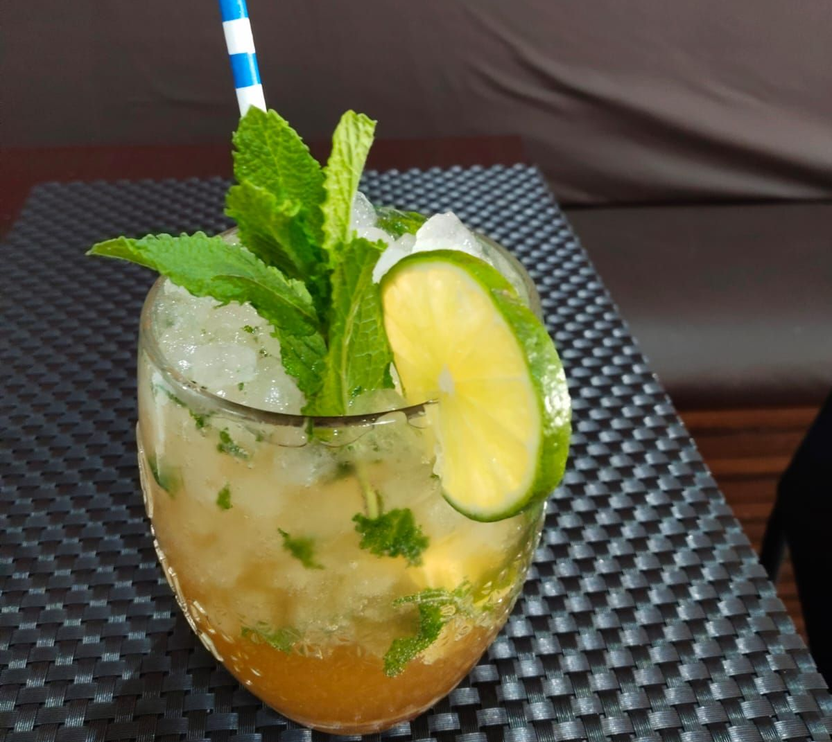 Cóctel rojo en una copa de martini junto a un pastel en la mesa de un café con el fondo desenfocado.