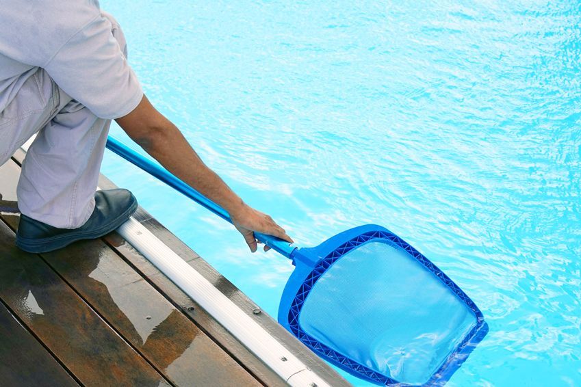 Una persona está limpiando una piscina con una red.