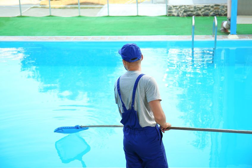 Un hombre está limpiando una piscina con una red.