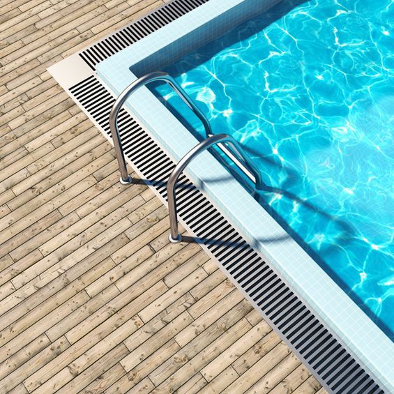 Una piscina con terraza de madera y escaleras.