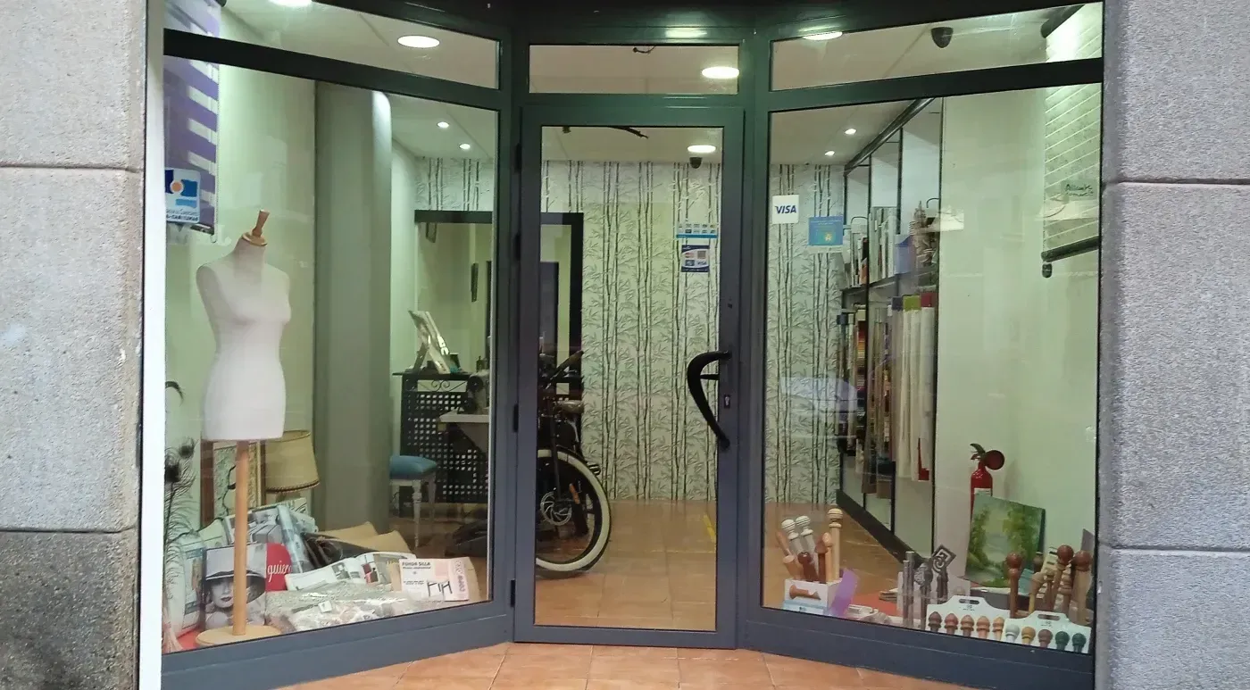 Un escaparate de tienda con maniquí, expositores y puerta de cristal.