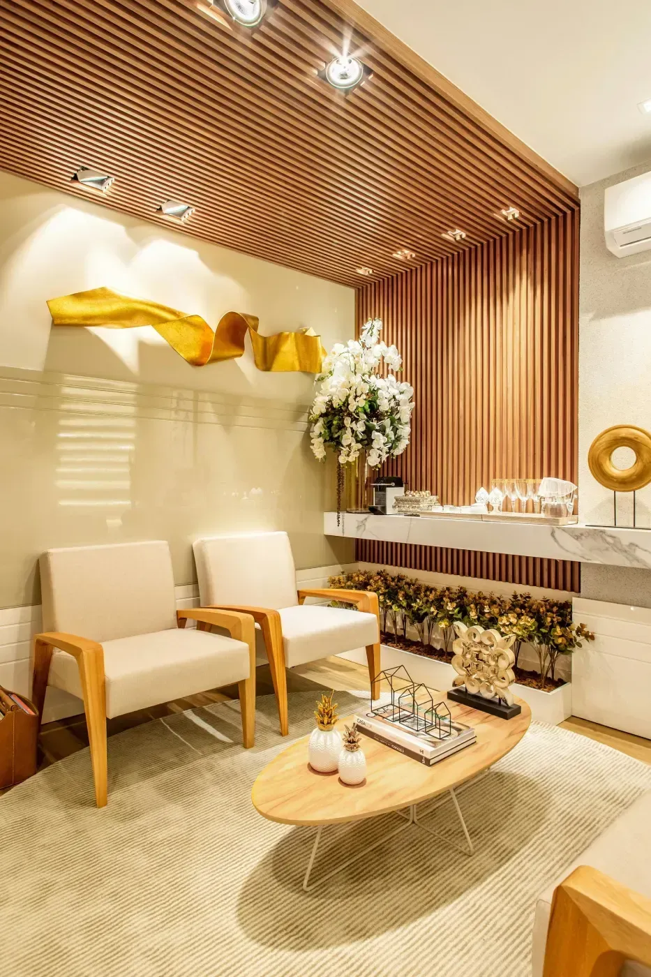 Acogedora sala de espera con sillas color crema, detalles de madera y una mesa de café baja sobre una alfombra color crema.