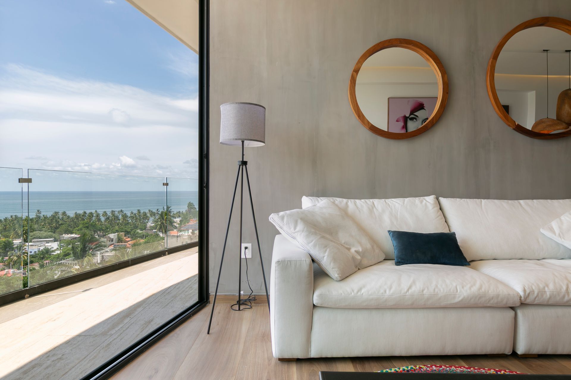 Living room with white sofa, floor lamp, mirrors, and ocean view.