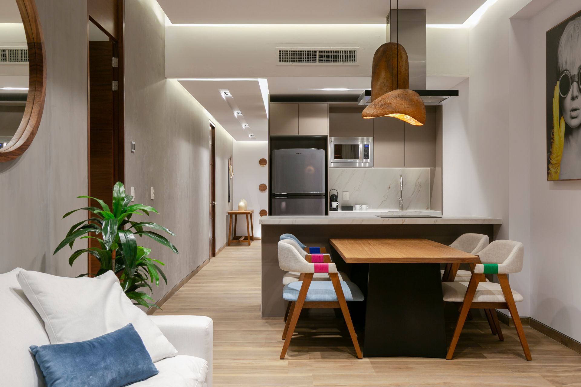 Modern apartment interior with kitchen island and dining area, light wood floors, and neutral color palette.
