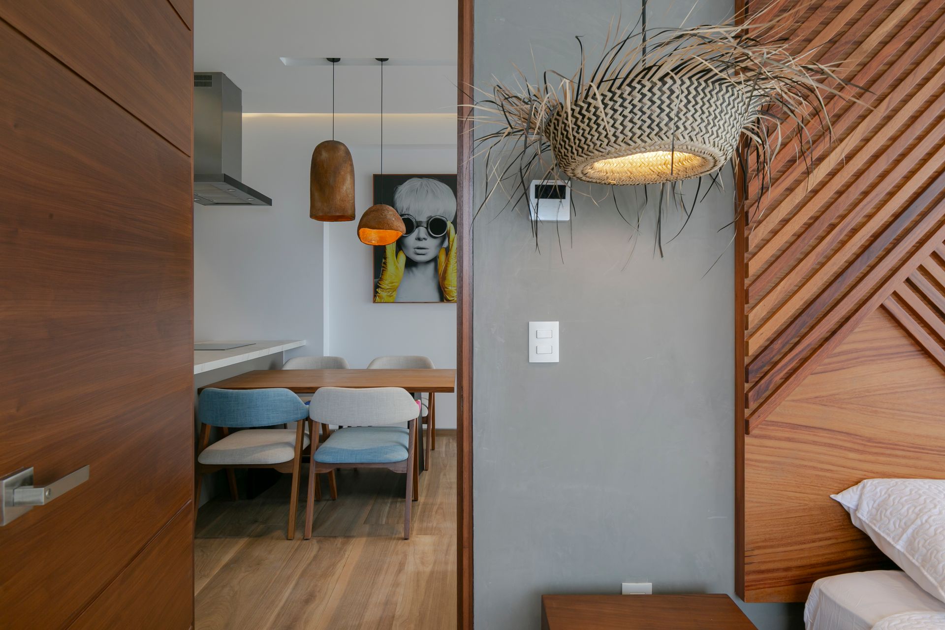 Bedroom interior with wood accent wall, view of dining area, and pendant lights.