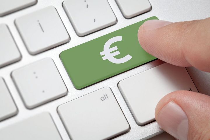 Presionando con el dedo la tecla verde del euro en un teclado blanco