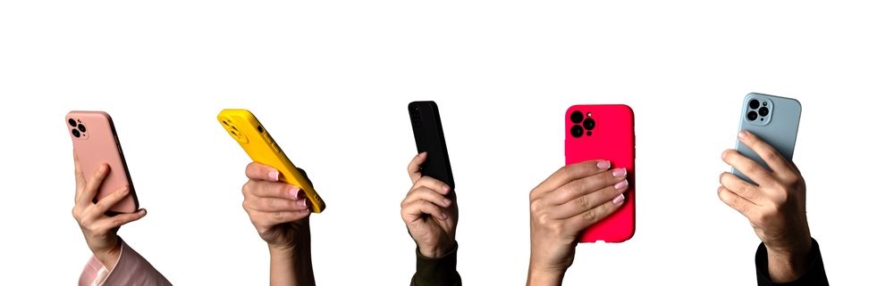 Manos sosteniendo cinco teléfonos inteligentes de diferentes colores sobre un fondo blanco.