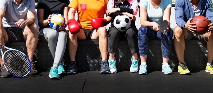 Plusieurs sportifs sont assis et tiennent chacun leur équipement dans leurs mains