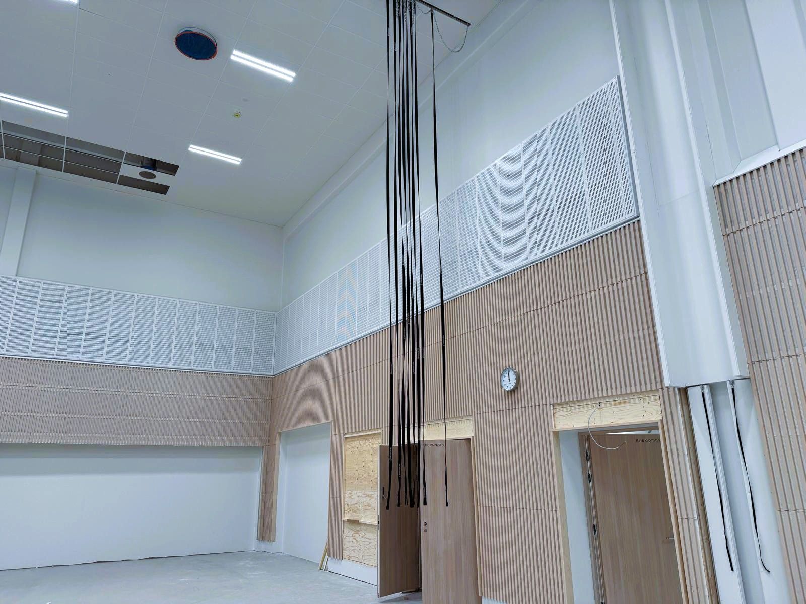Moderni sisäatrium, jossa on korkeat valkoiset seinät, riippuvia kaapeleita ja suuri avoin kattotila.