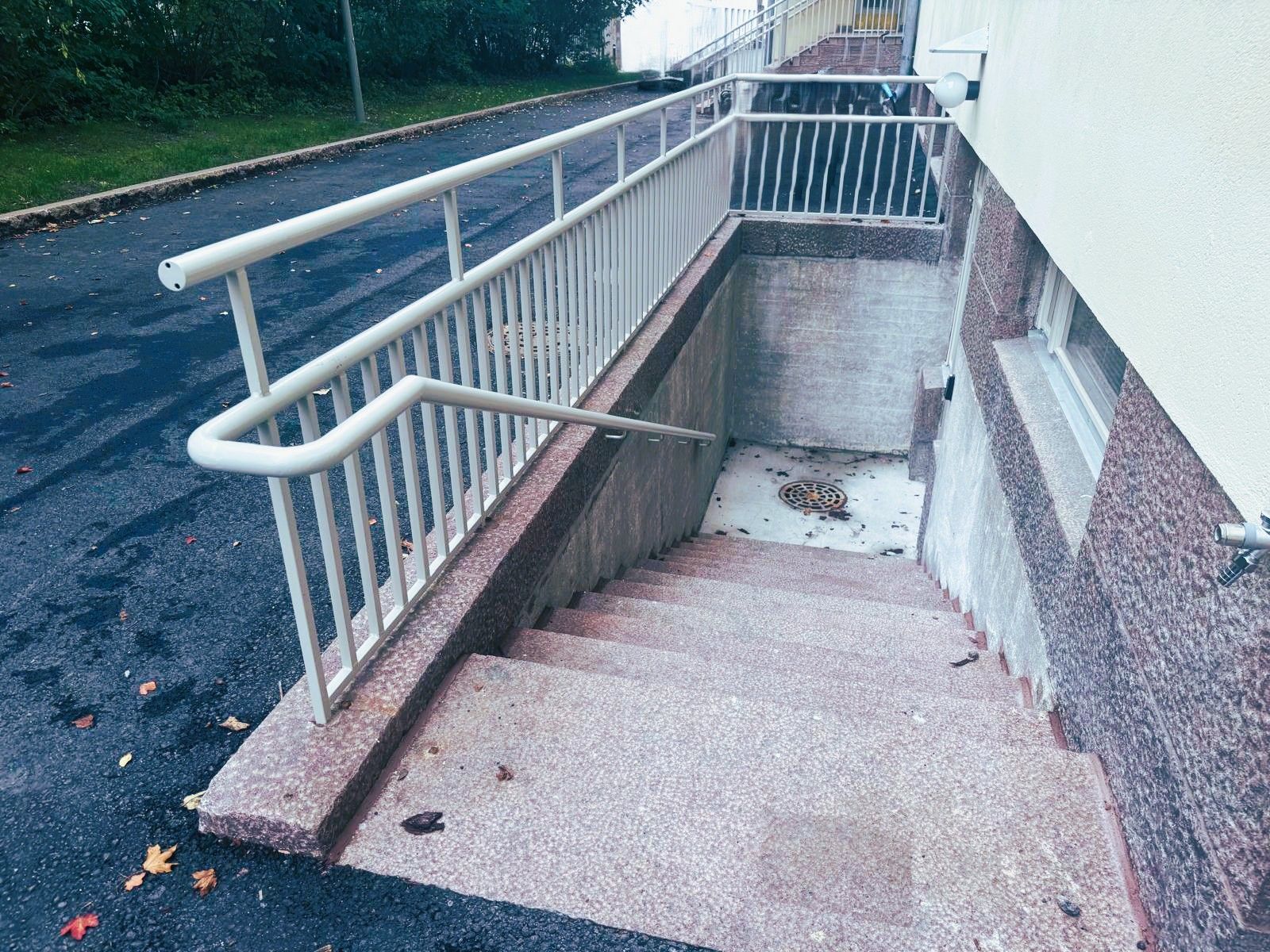 Jyrkkä ulkoluiska, jossa on metallikaiteet rakennuksen vieressä ja joka johtaa alas alemmalle tasolle