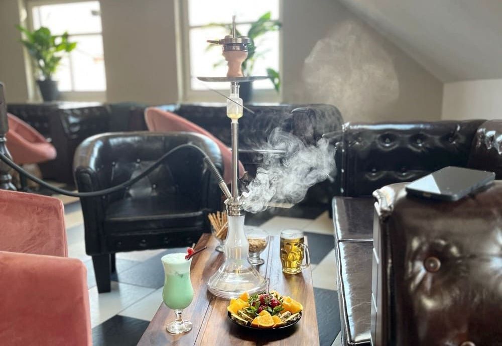Eine Person raucht eine Wasserpfeife auf einem Tisch in einem Restaurant | By Mikey
