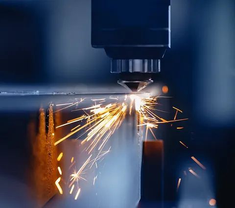 Una máquina está cortando un trozo de metal del que salen chispas.