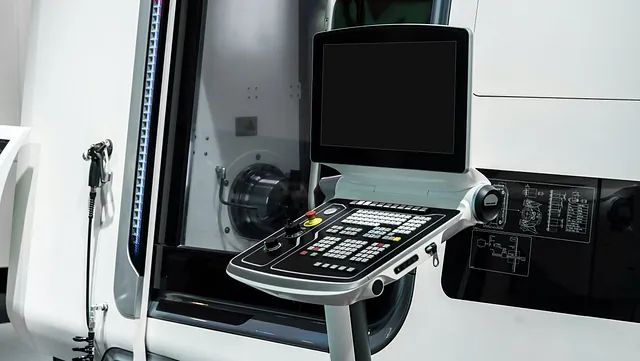 Un monitor de computadora está sobre una mesa al lado de una máquina.